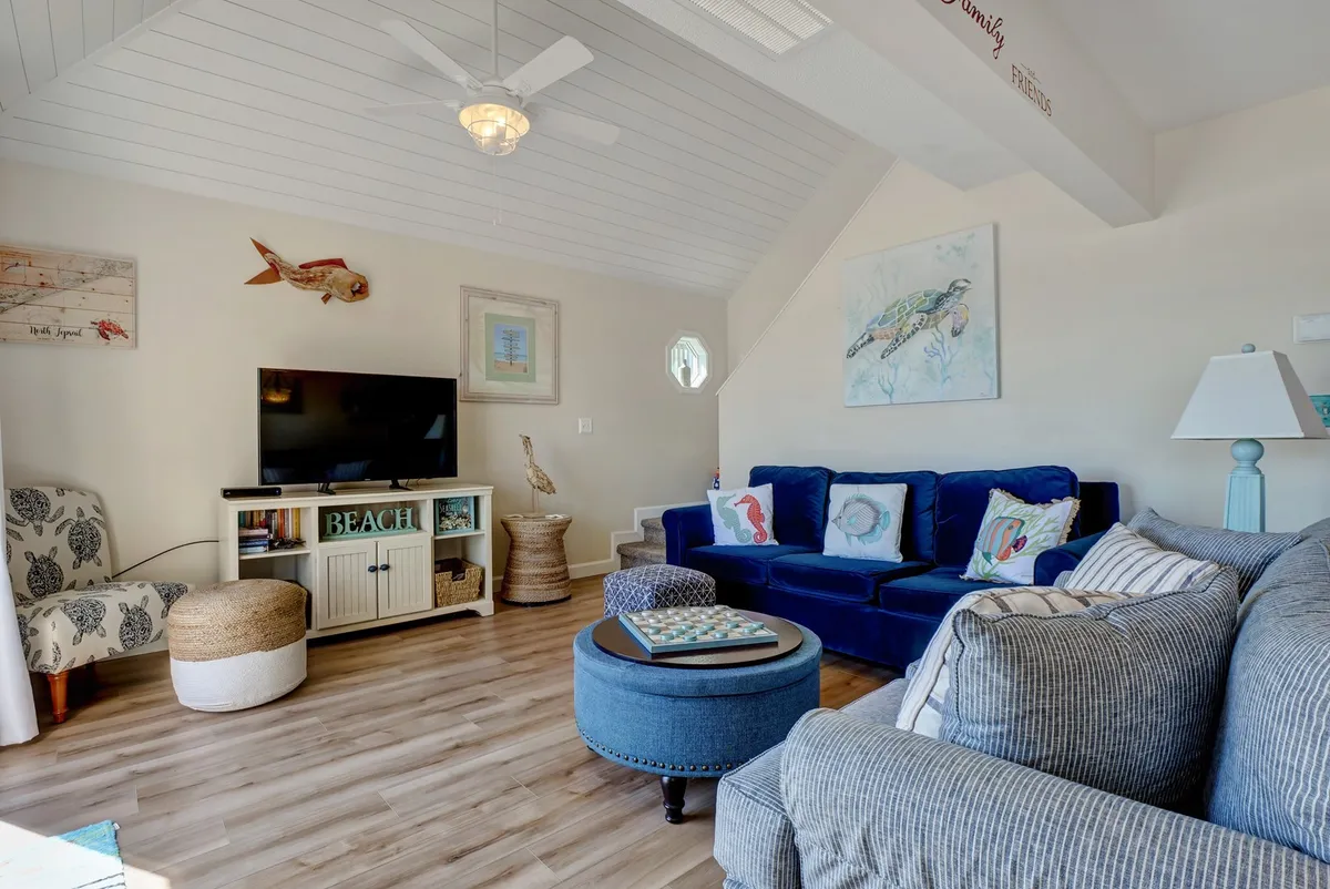 This image highlights a blue couch with decorative pillows, a coffee table, and a television set in a casual, coastal-themed living area. The seating is arranged to foster conversation and relaxation, with the TV as a focal point for movie nights or entertainment.