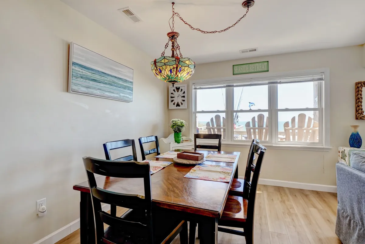 A welcoming dining area features a table under a stained glass chandelier, with a window offering a glimpse of the outdoors. The scene is warm and communal, suggesting morning breakfasts before heading out or evening meals recounting the day’s adventures.