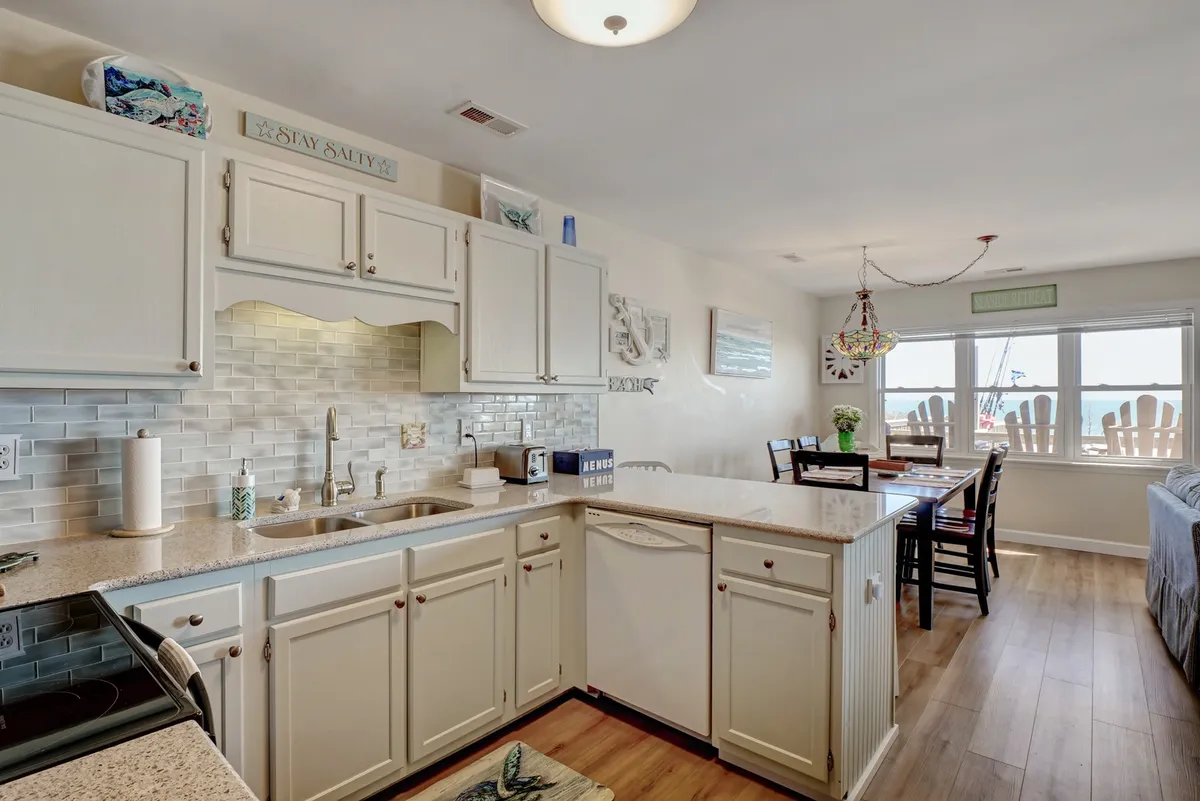 A cozy and inviting kitchen and dining area featuring a large countertop, a welcoming dining table, and windows that allow natural light to fill the space. The setting suggests a comfortable, home-like environment ideal for shared meals or gathering with loved ones.
